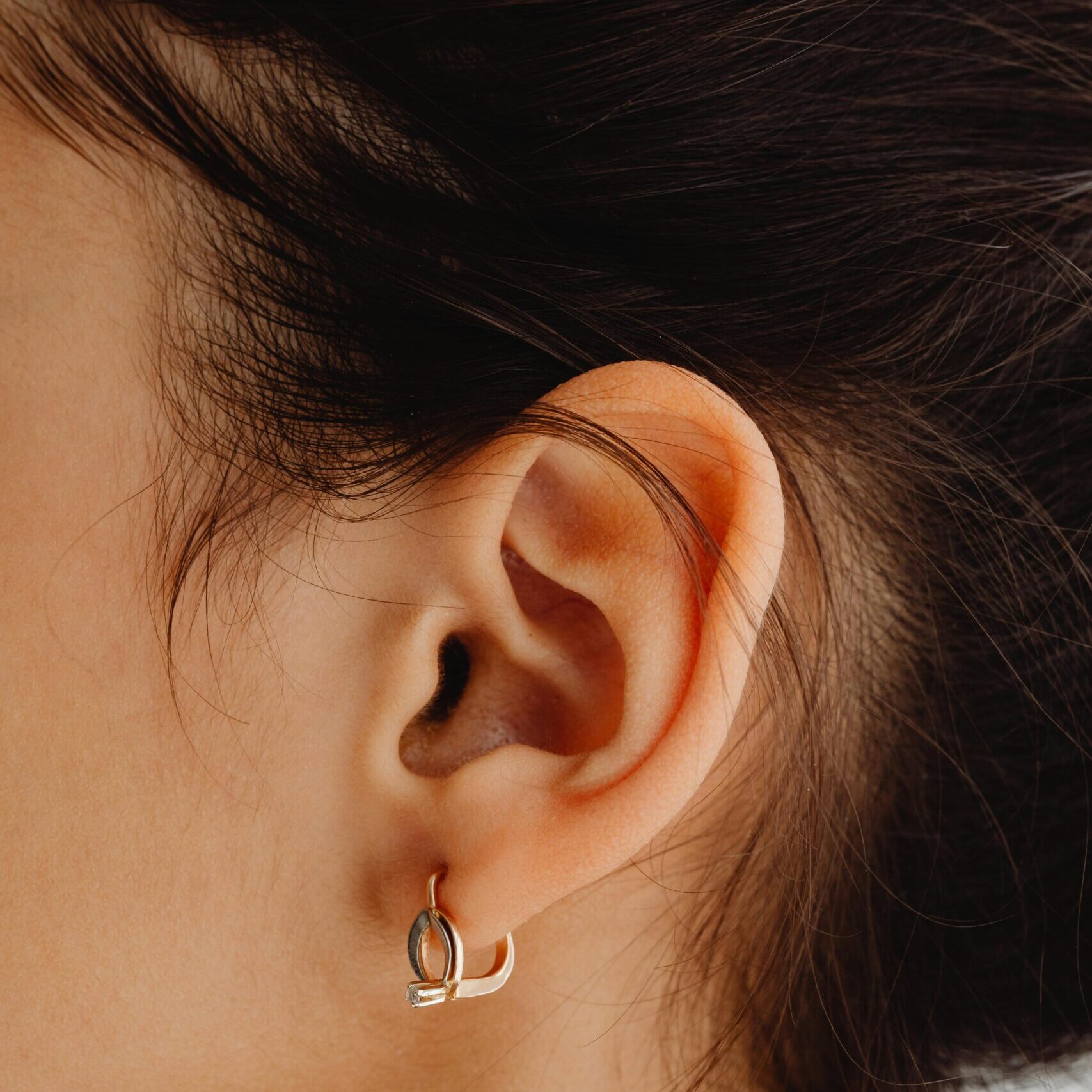 Detailed close-up of an ear adorned with a stylish earring, featuring fine hair texture.